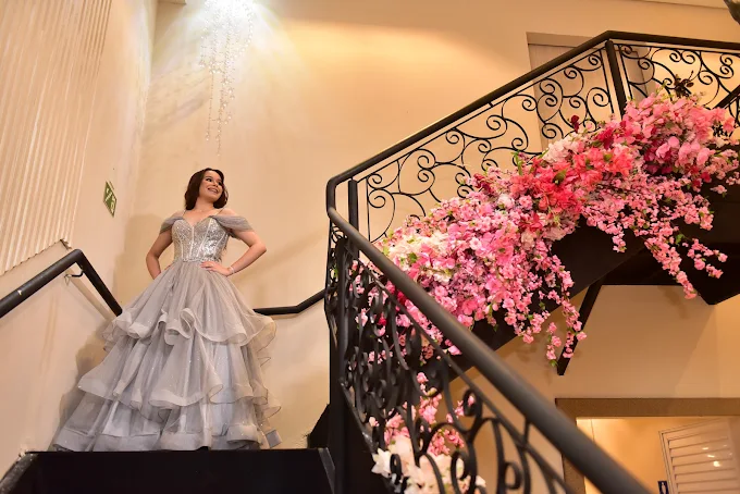 Debutante em escadaria decorada com flores cor-de-rosa